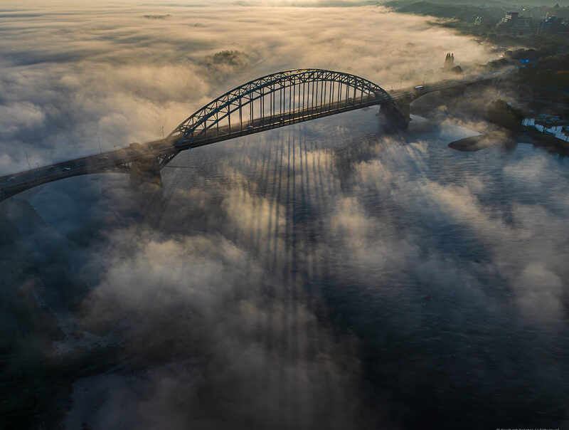 Lange schaduwen van de Waalbrug op de mist, in de vroege ochtend.